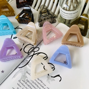 Detail of colorful hollow triangle hair claws in glossy resin displayed on magazine