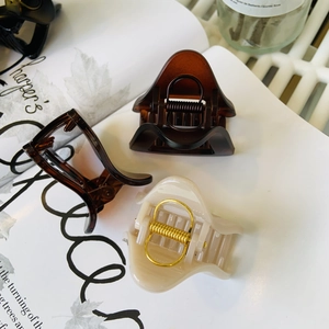 Close-up of cream and tortoiseshell triangle hair claw clips with strong gold metal springs