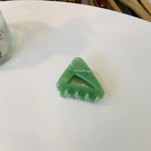 Détail d'une pince à cheveux triangulaire verte avec texture marbrée et fini acétate
