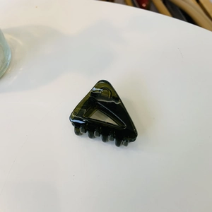Vue détaillée d'une pince à cheveux triangulaire vert foncé translucide avec dents