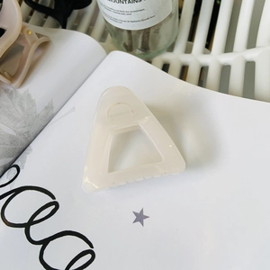 Detail of a creamy beige triangular hair claw clip showing smooth finish and hollow design