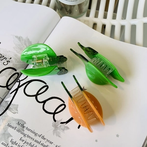 Detailed view of colorful fruit-themed acetate hair claws in green and orange tones