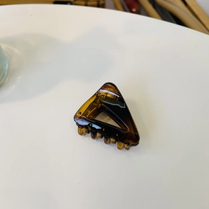 Détail d'une petite pince à cheveux triangulaire creuse avec texture ambre écaille
