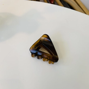 Détail macro d'une pince à cheveux triangulaire ambre avec dents de maintien solides