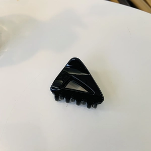Détail d'une petite pince à cheveux triangulaire noire brillante au design creux