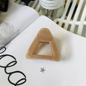 Detail of a nude triangular shark hair clip on a book with soft natural lighting