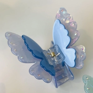 Macro shot of iridescent acetate double-layered butterfly hair claw clip with rhinestones