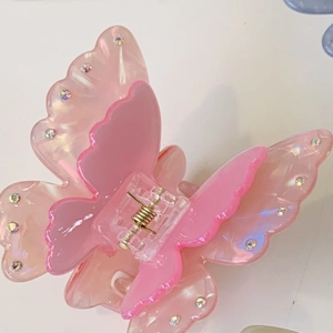Detail of pink acetate butterfly hair claw clip with colorful rhinestones and gold spring