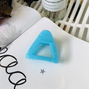 Close-up of light blue hollow triangle hair claw clip on white magazine background