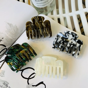 Set of four premium acetate claw clips with marble textures and gold lettering