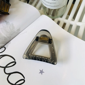 Minimalist hollow triangle shark hair clip in dark grey resin with golden metal spring