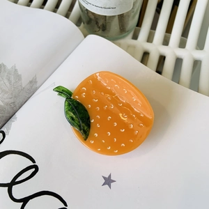 Detail of cellulose acetate orange claw clip with glossy finish on a white book