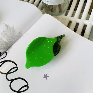 Detailed macro view of a bright green lemon shaped acetate hair claw clip with leaf
