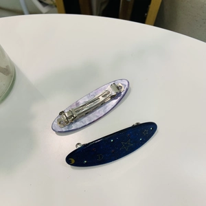 Détail du motif marbré et du design céleste lune et étoiles sur les pinces à cheveux