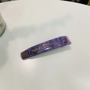 Détail de la pince à cheveux créative en acétate violette, design tube de dentifrice pailleté