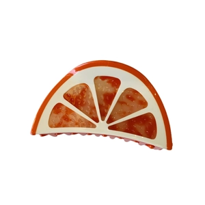 Vibrant orange slice acetate hair claw clip with ivory accents and a glossy finish