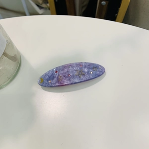 Détail d'une pince à cheveux avec motifs étoile et lune sur un dégradé bleu-violet