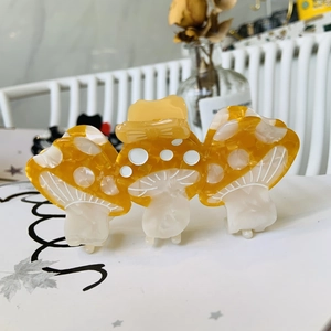 Macro shot of three connected yellow and cream mushroom acetate hair claws on a stand