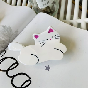 Pince à cheveux chat blanc mignon en acétate sur fond de magazine blanc pur
