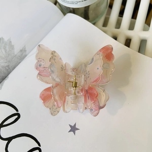 Détail d'une pince à cheveux papillon double couche en acrylique avec motifs floraux