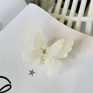 Close-up of a white translucent butterfly hair claw clip with silver glitter details