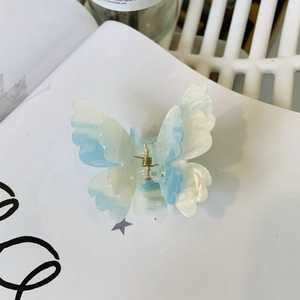 Detail of gradient blue butterfly hair claw with glitter finish on a white book