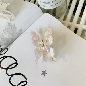 Détail de la pince à cheveux papillon en acétate rose marbré avec ressort en métal doré
