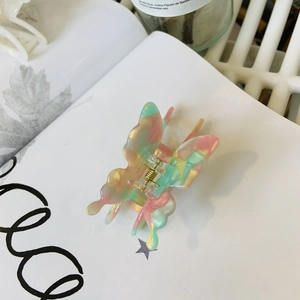 Gros plan d'une pince à cheveux papillon en acétate marbré coloré translucide