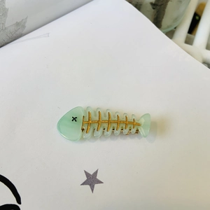 Détail d'une pince à cheveux en forme d'arête de poisson vert menthe avec touches dorées