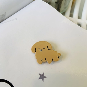 Détail d'un pin's en émail caniche kaki mignon sur papier blanc avec étoile