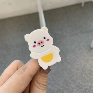 Détail d'une mignonne pince à cheveux cochon en acétate blanc avec des accents roses et jaunes