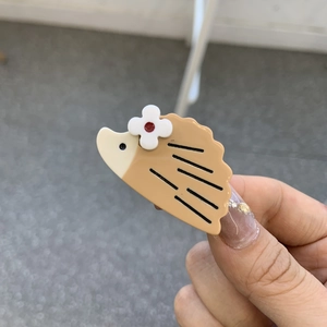 Vue détaillée d'une barrette hérisson en résine acétate marron avec une petite fleur