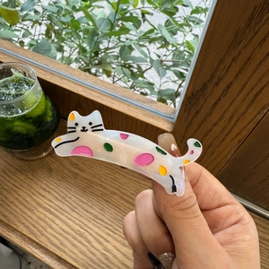 Détail d'une pince à cheveux en acétate en forme de chat avec des pois colorés