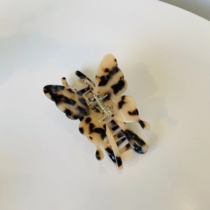 Pince à cheveux papillon élégante en acétate avec motif écaille de tortue sur fond blanc