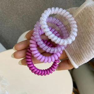 Detailed macro of four-piece spiral telephone cord hair ties in assorted purple shades