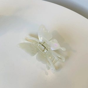 Vue détaillée latérale de la pince à cheveux papillon en acétate blanc perle et ressort