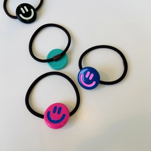 Dettaglio di elastici per capelli in acetato colorato con ciondoli a faccina sorridente
