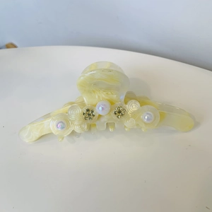 Détail d'une pince à cheveux en acétate avec texture marbrée crème et perles chic