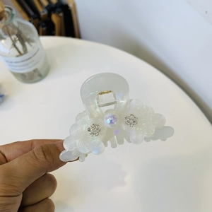 Elegant white acetate hair claw clip with pearl flower and shimmering rhinestone details