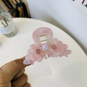 Elegant pink acetate hair claw clip with pearlescent floral accents and gold spring detail
