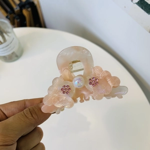 Detail of pink acetate hair claw clip with pearl petal and sparkling rhinestones
