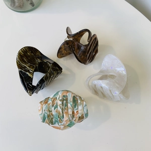 Macro view showing 4 acetate shark hair clips in marble and pearlescent floral patterns