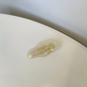 Handmade iridescent amber resin hair clip for women with gold logo on white background