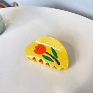 Macro shot of French acetate yellow hair claw with orange tulip flower pattern