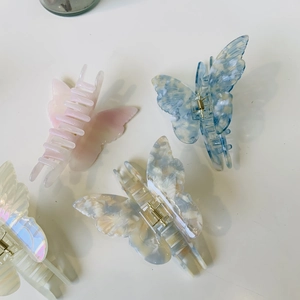 Detail view of four colorful acetate butterfly hair claws with glossy shell texture