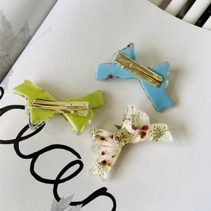 Detailed view of three floral bow hair clips with real dried flowers and gold metal base