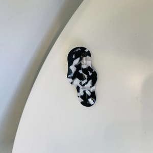Close-up of handmade irregular black and white marble acetate hair clip with gold text