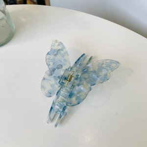 Detail of blue marble butterfly hair claw clip with golden metal spring for women