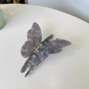 Detailed macro view of acetate butterfly hair claw with purple marble texture and gold spring
