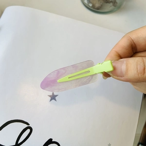 Fermaglio per capelli in acrilico viola marmorizzato e verde pastello in mano
